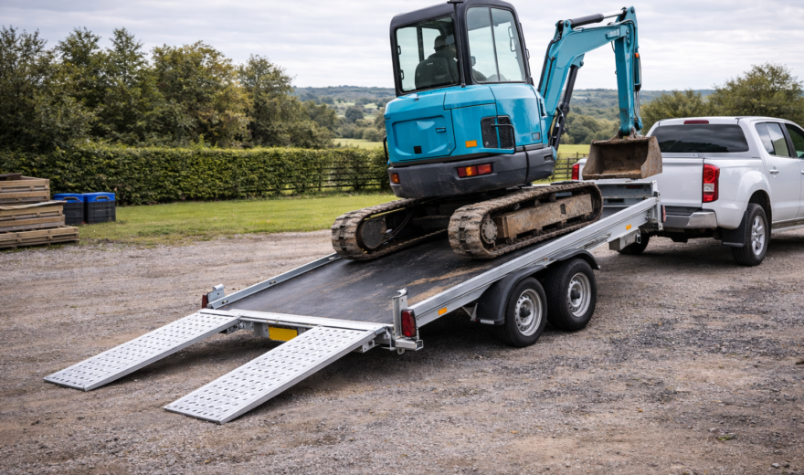 Excavator loading onto tilt-bed trailer
